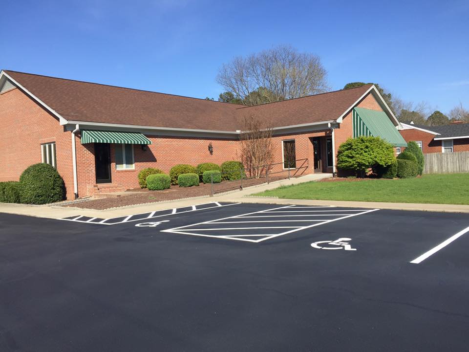 Parking spaces in front of brick building with green and white striped awnings