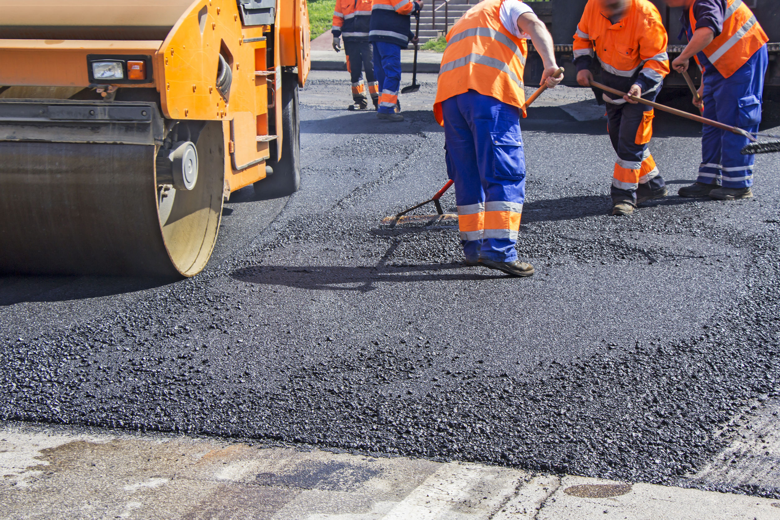 Roller and workers on asphalting and repair of city streets