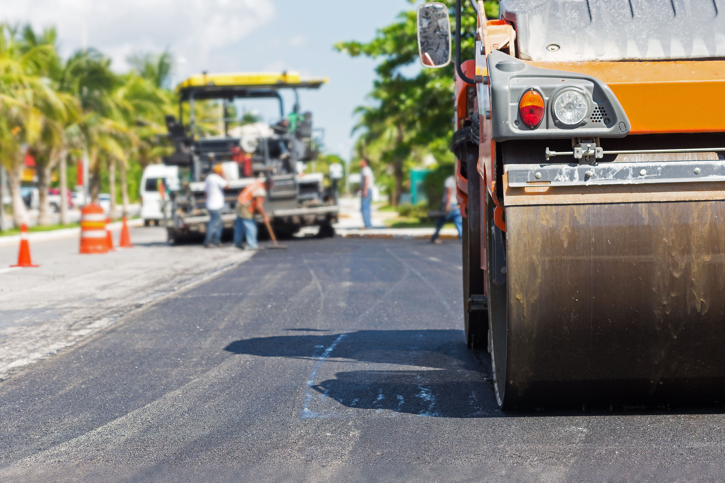 Road construction works with steamroller machine and asphalt finisher